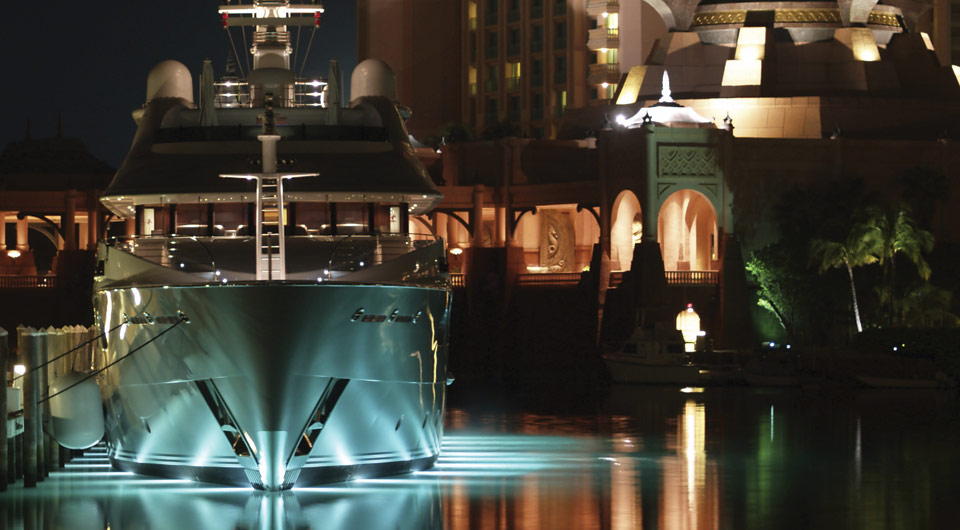 An image of a yacht in a luxury marina at night.